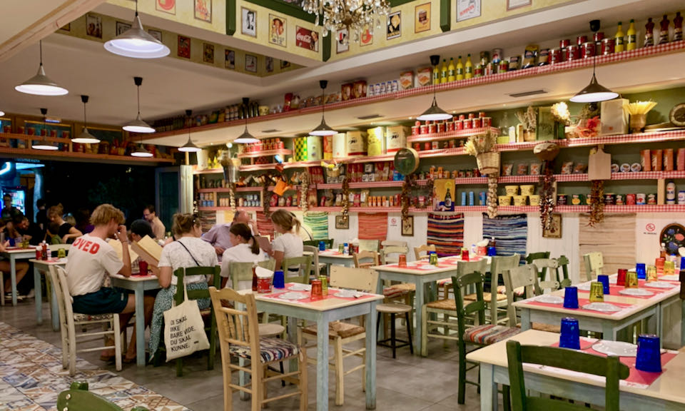 A group of diners sits at a table surrounded by colorful jars and boxes.