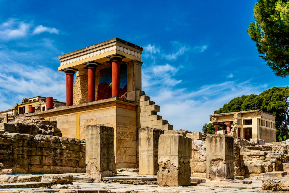 Photo of Knossos palace ruins showing brightly-painted columns and a bull fresco