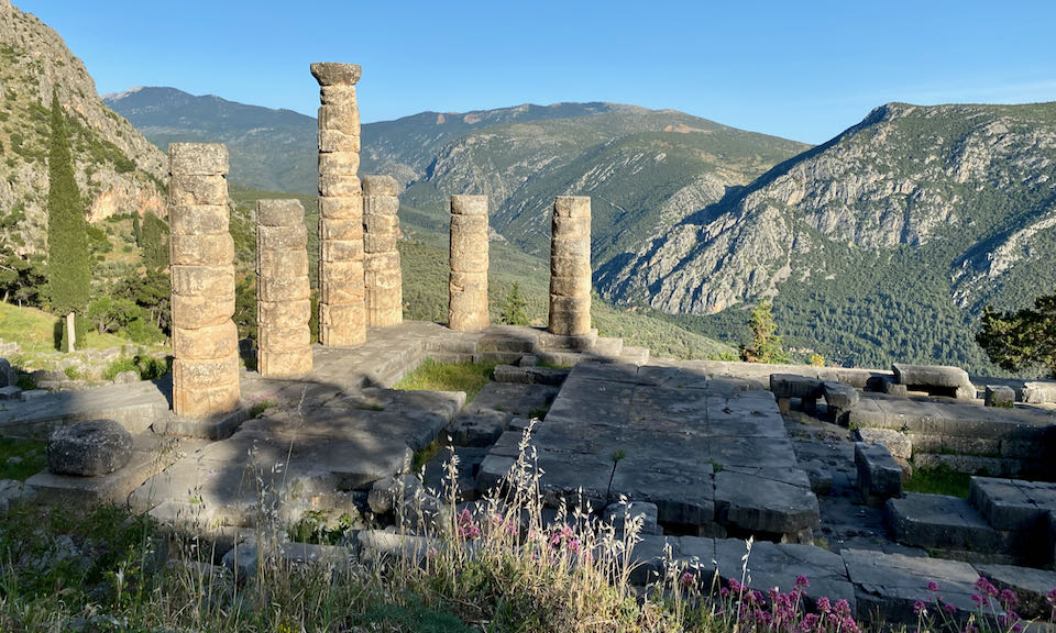 Ancient stone pillars stand in sunset light against a mountain backdrop