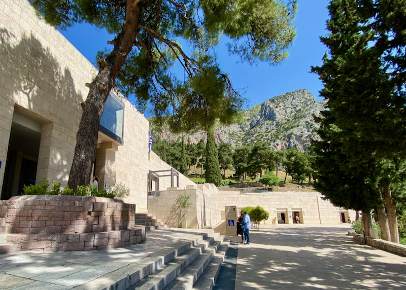 Exterior of a boxy stone museum with a mountain backdrop