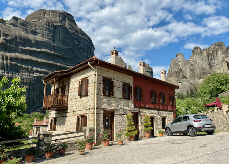 Small stone hotel in front of a large limestone pillar
