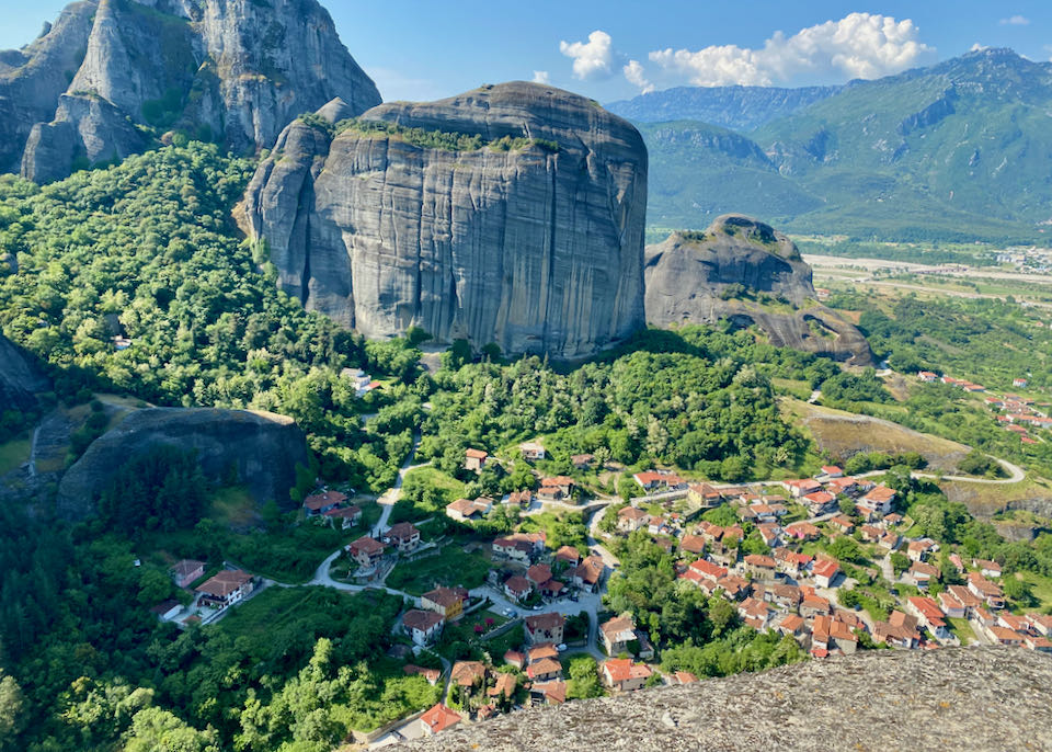 Red-roofed buildings seen from above in a landscape of lush green trees and gigantic rock formations