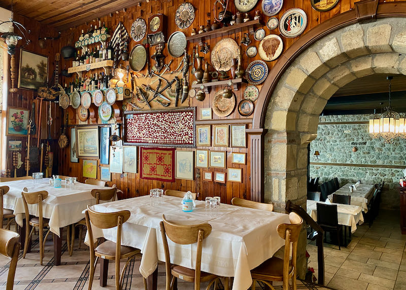 Set tables with white tablecloths against a rustic stone wall covered in memorabelia