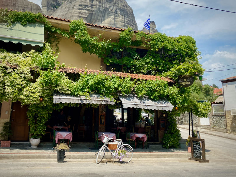 Vine-covered restaurant with an outdoor terrace and a vintage bike out front