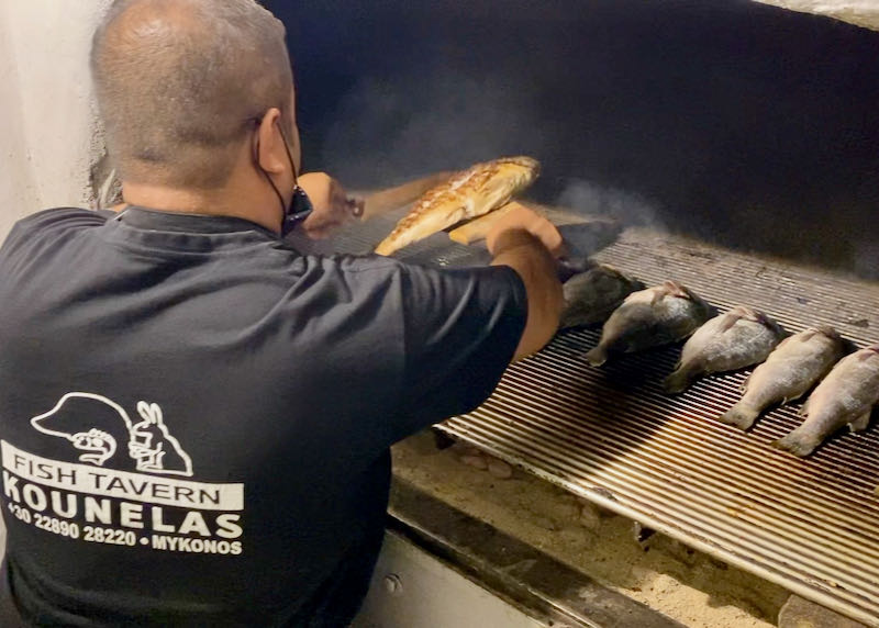 A man flips a fish on a hot grill