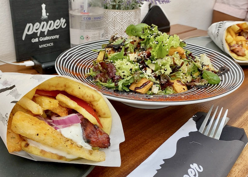 A souvlaki gyro wrap and a salad on a table set for lunch