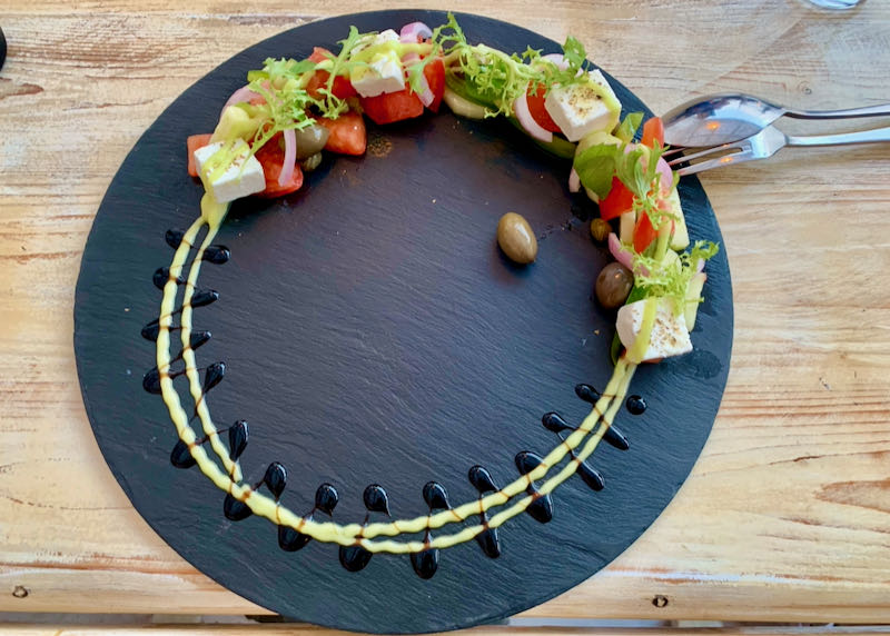 Artistically-presented greek salad on a round, slate platter