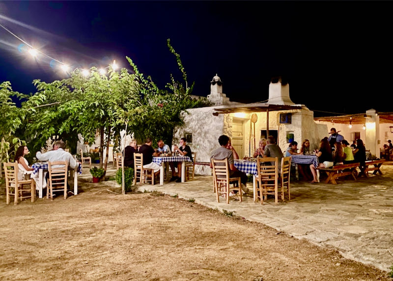 Diners at outdoor tables in a rustic setting at night