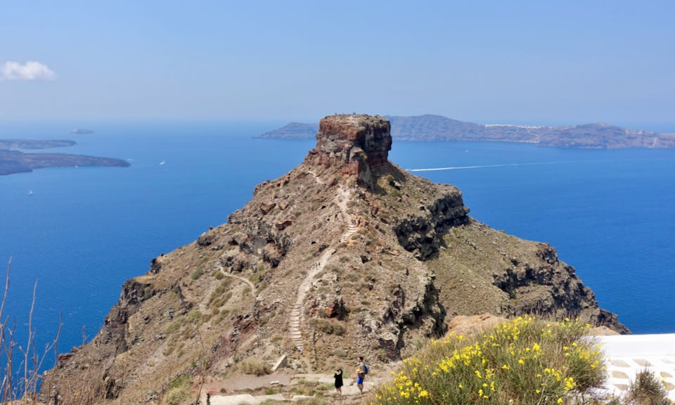 Large rock formation overlooking the Santorini Caldera, with a hiking trail leading out to it