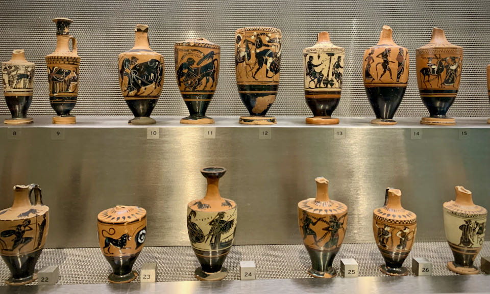 Red and black clay vases lined up in a glass museum display
