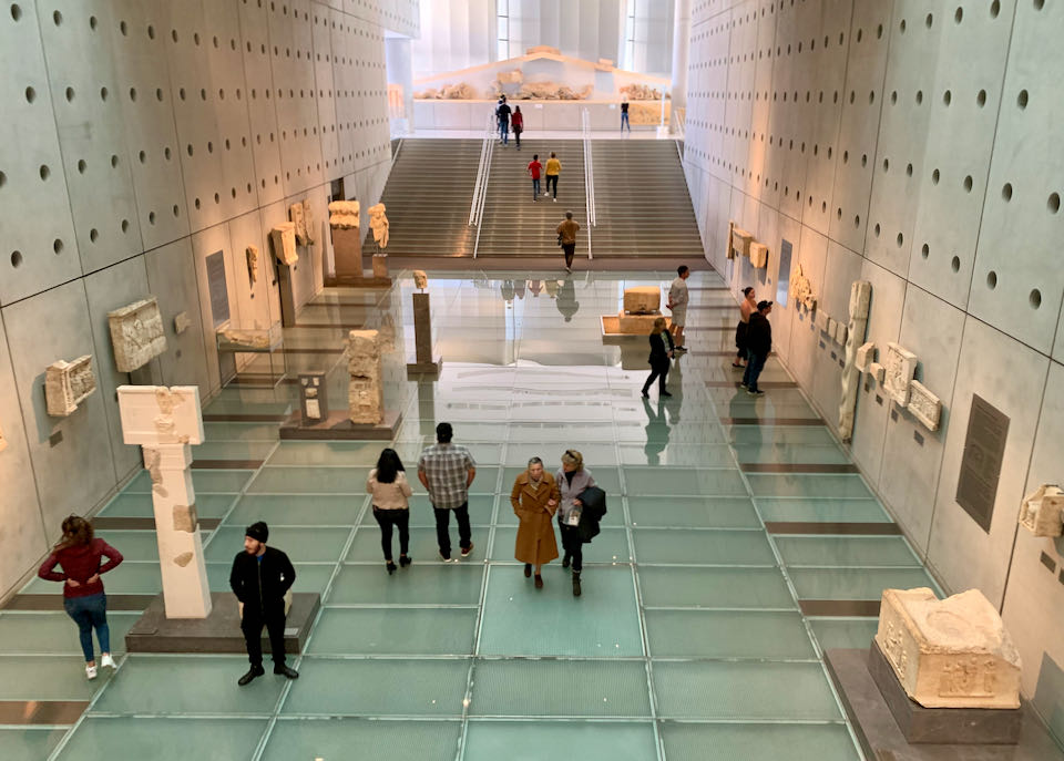Large museum corridor with glass floors and a staircase at the end