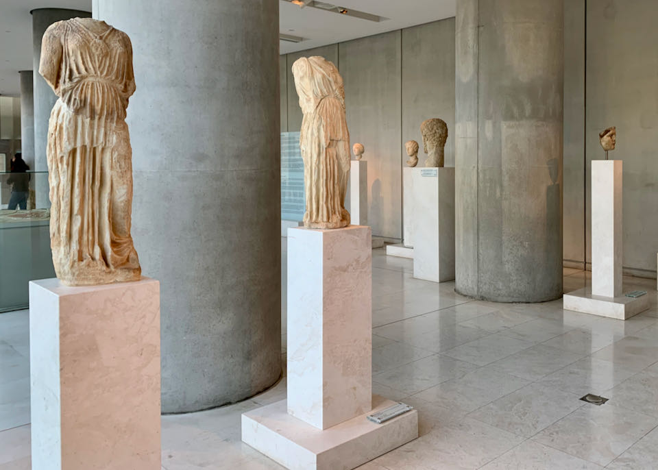 Marble sculptures of women's forms atop pedestals in a museum