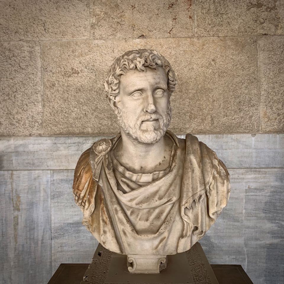 Marble bust of a man with curly hair and a beard, dressed in draping garments