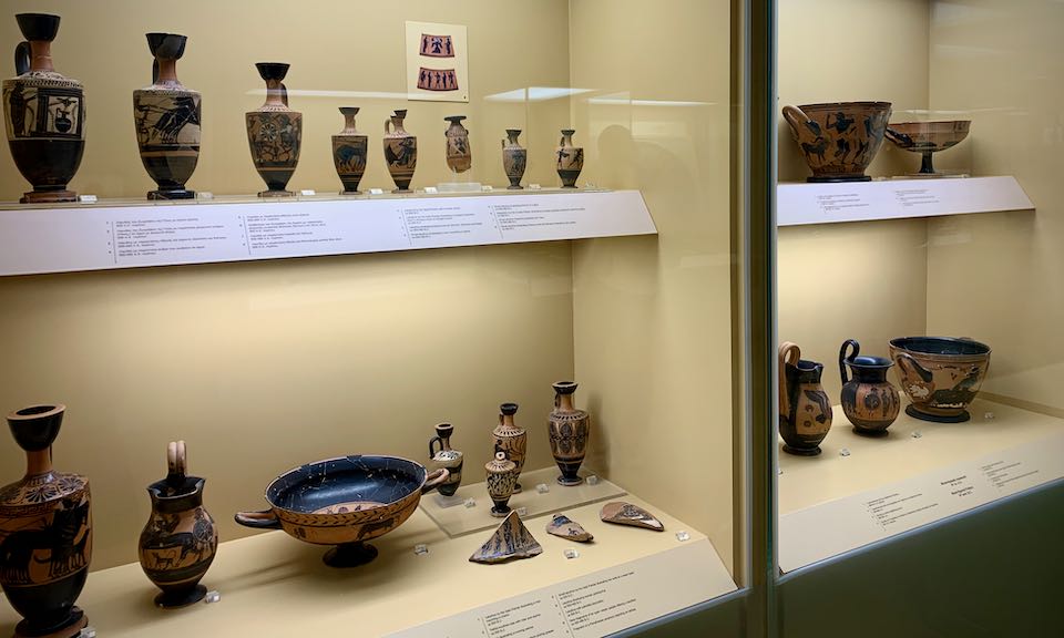 Red and black Greek vessels in a museum display case