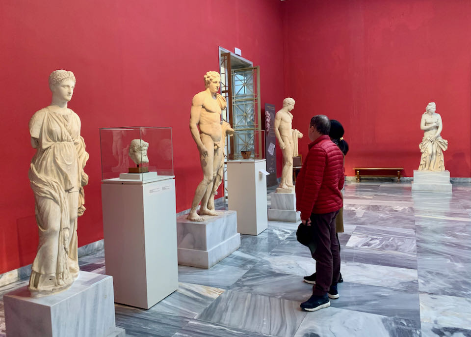 A man looks at marble sculptures in a museum