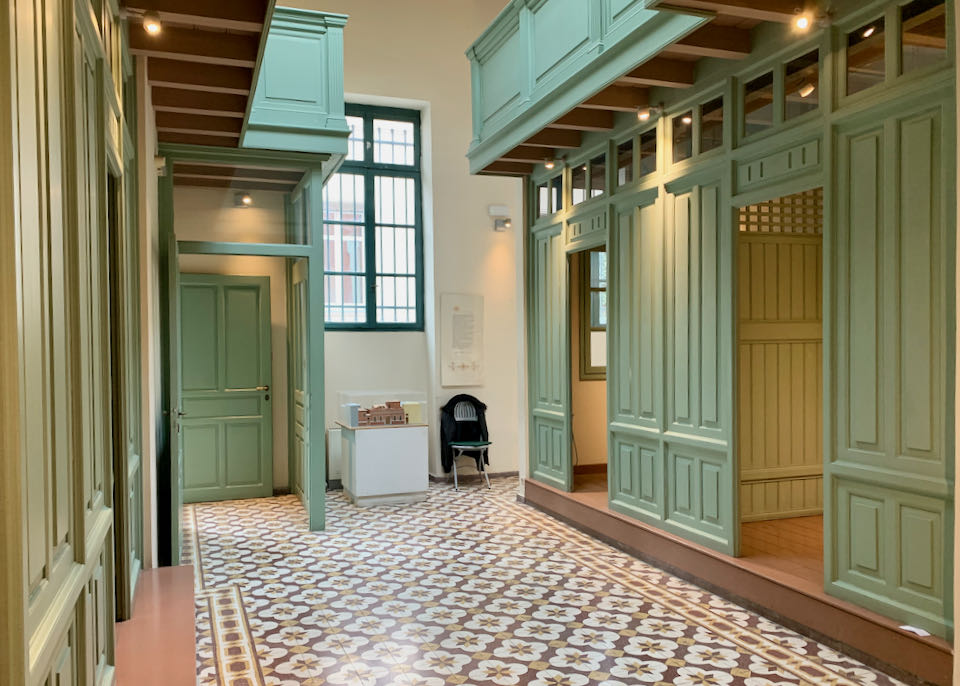 Large tiled corridor surrounded by loght-green painted wooden stalls