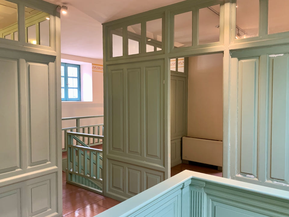 Upstairs staircase landing with green-painted wood stalls