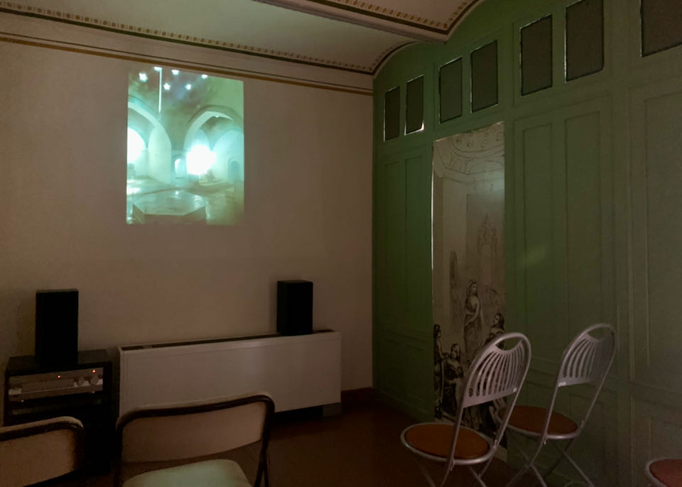 Darkened room with an image of a bathhouse projected on the wall