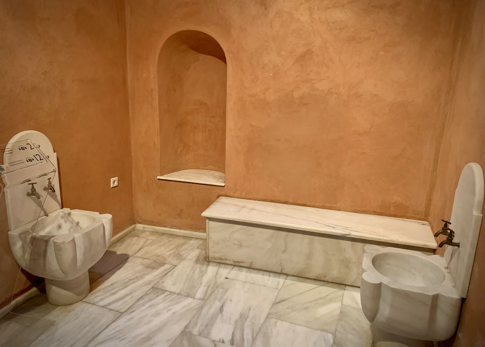 Room with terra cotta walls and marble bench and basins
