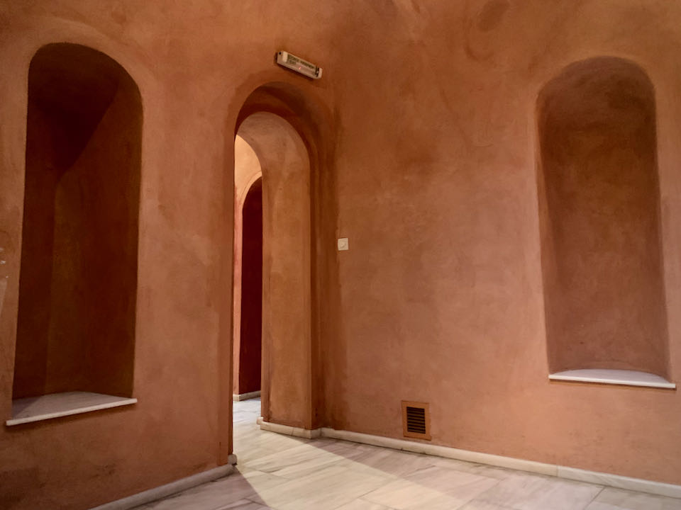 Room with terra cotta walls, marble floors, and an arched doorway