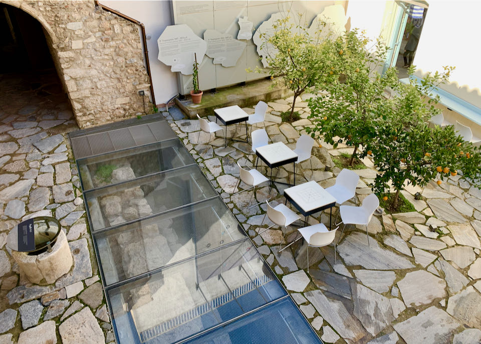 View looking down at a stone courtyard with cafe tables and orange trees