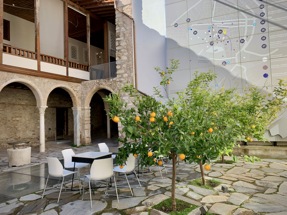 Tables set beside orange trees in a stone courtyard