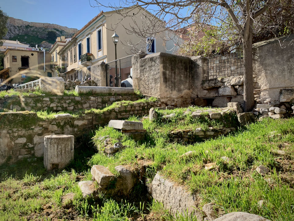Ruins of an ancient olive press, with modern Athenian buildings in the background