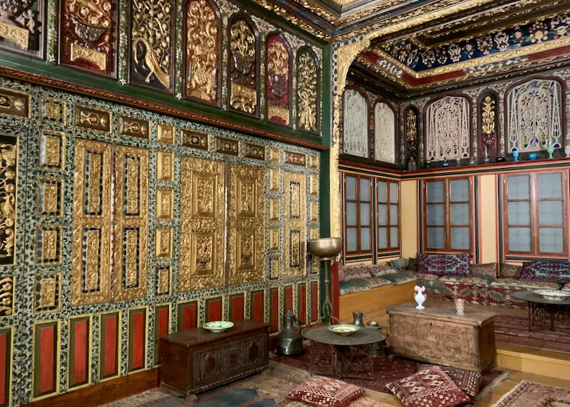 Ornate room covered from floor to ceiling with rich tapestries and carved woodwork