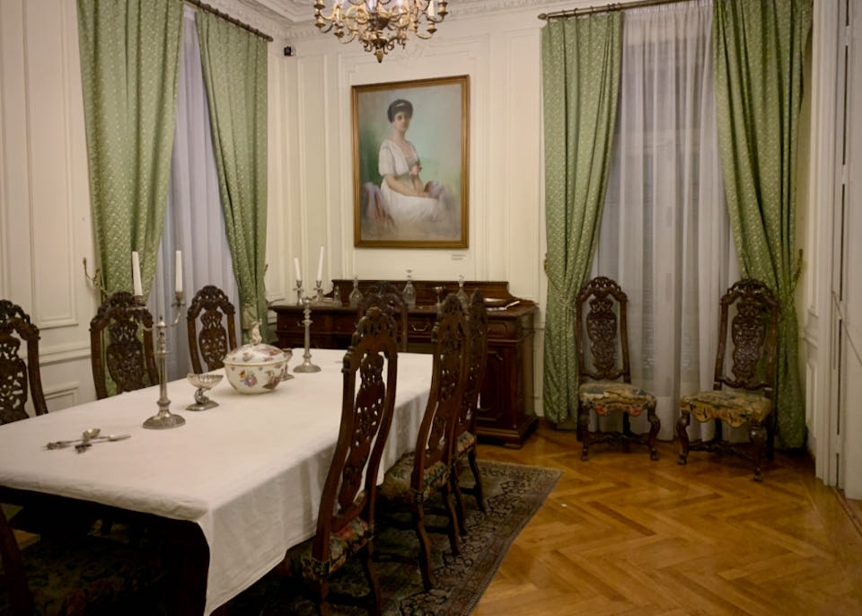 Elegant dining table in a room with green-curtained windows and a lovely oil painting