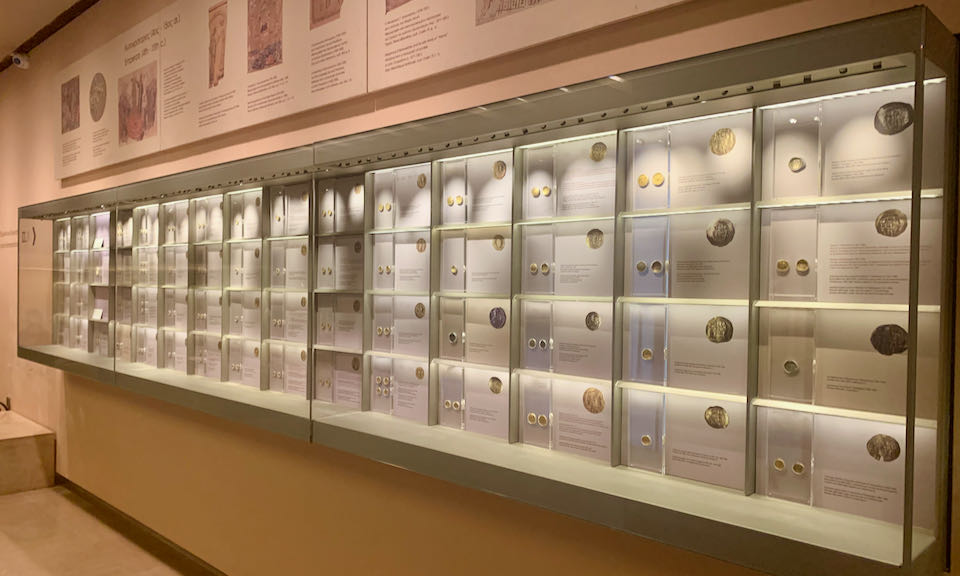 Display of ancient currency coins on a museum wall