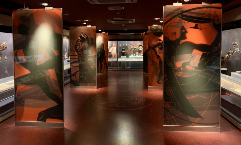 Museum gallery with large murals of daily life in ancient Greece
