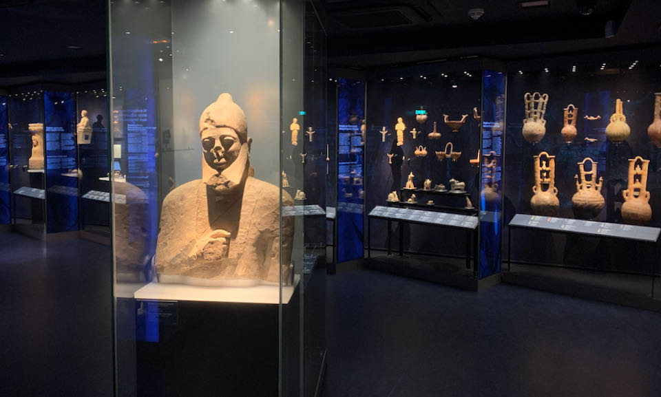 Darkly-lit room filled with displays of ancient sculpture