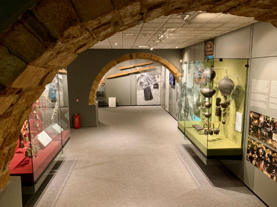 View through a stone archway to a room with musical intstruments in display cases