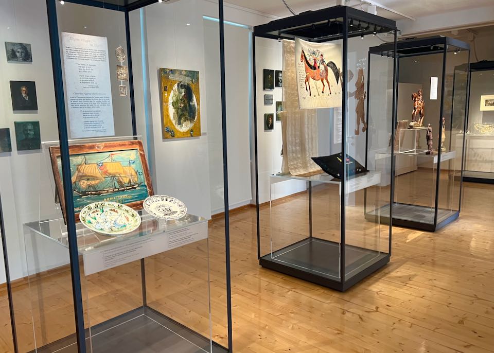 Museum display cases next to oil paintings displayed on a gallery wall