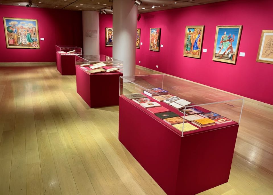 Gallery space with fuschia walls and display cabinets