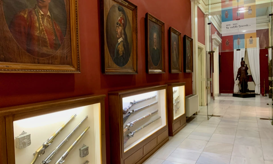 Hallway lined with paintings and old guns
