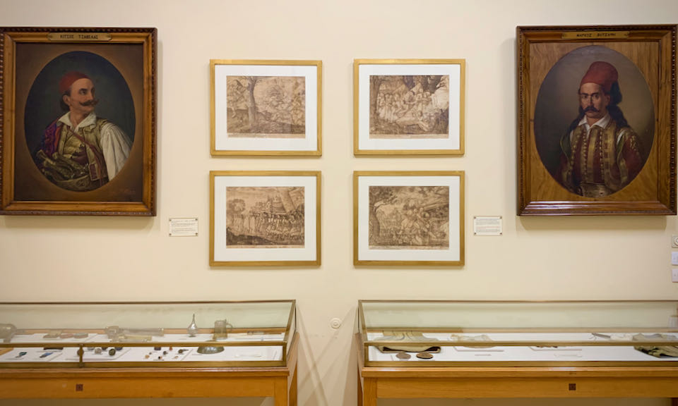 Paintings on a wall above a museum display case
