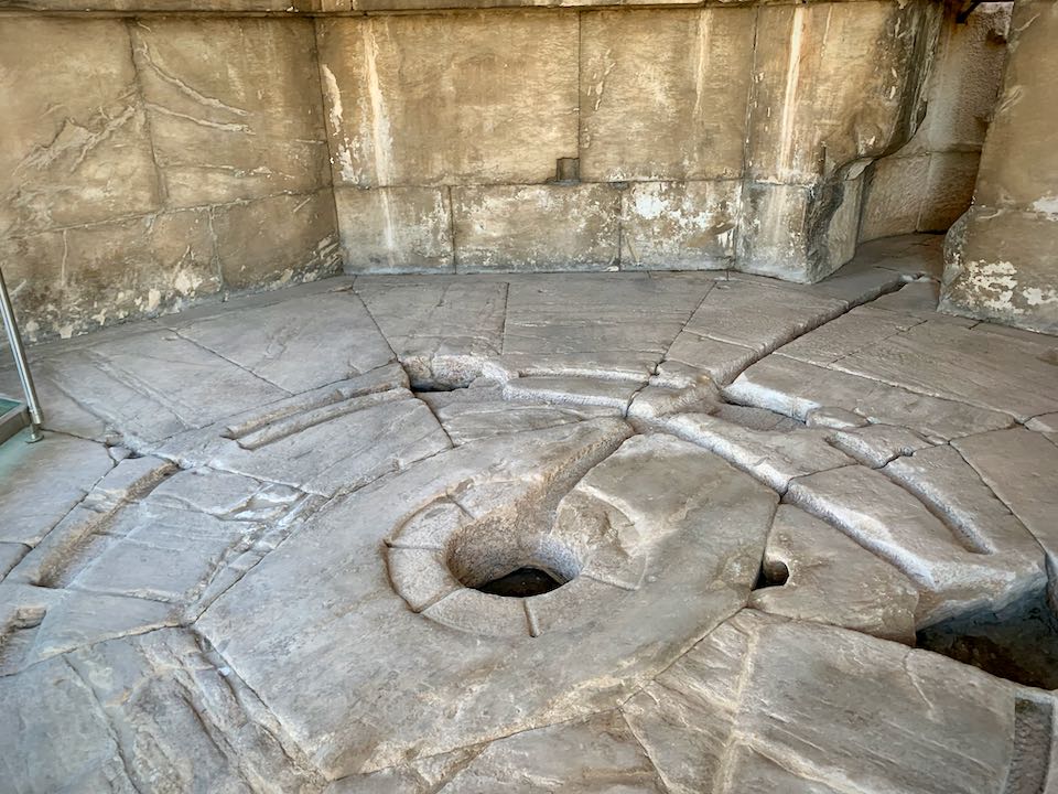 Marble floor with a hole in the middle and notches carved out.