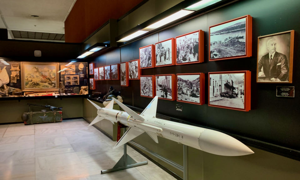 Missle displayed alongside black and white photos of Greek soldiers