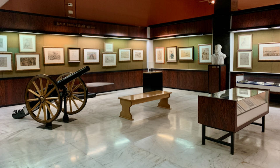 A cannon displayed in a room full of military artwork