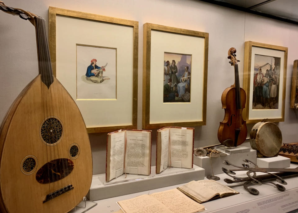 Traditional Greek instruments and antique books on display in a museum case