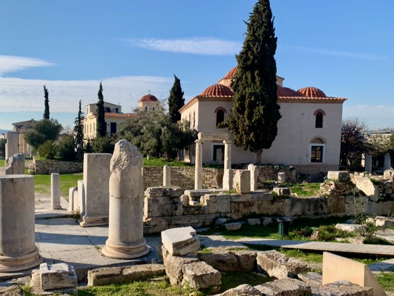 Byzantine-stile mosque near columnular cypress trees and ancient ruins.
