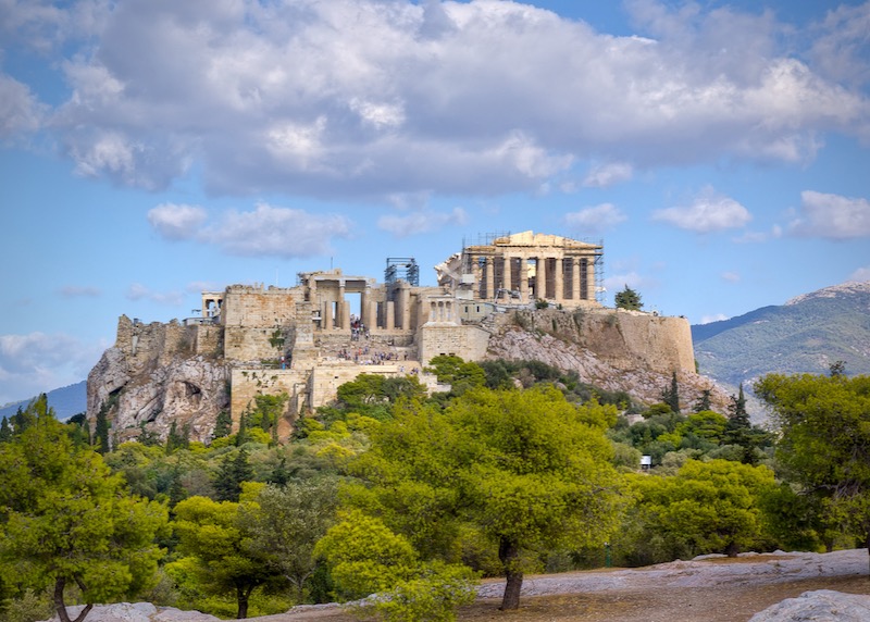 The ancient marble temple ruins of the Athens Acropolis, set against a blue sky 