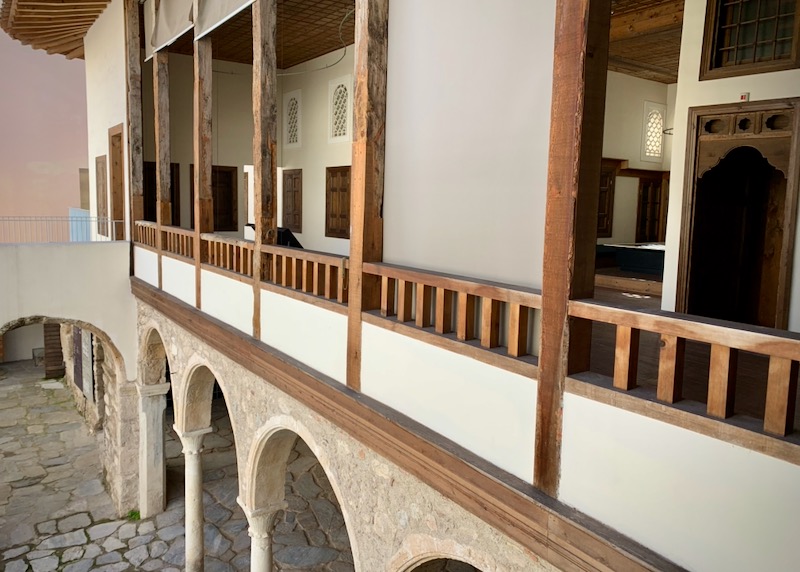 View down a wooden balcony to stone archways below