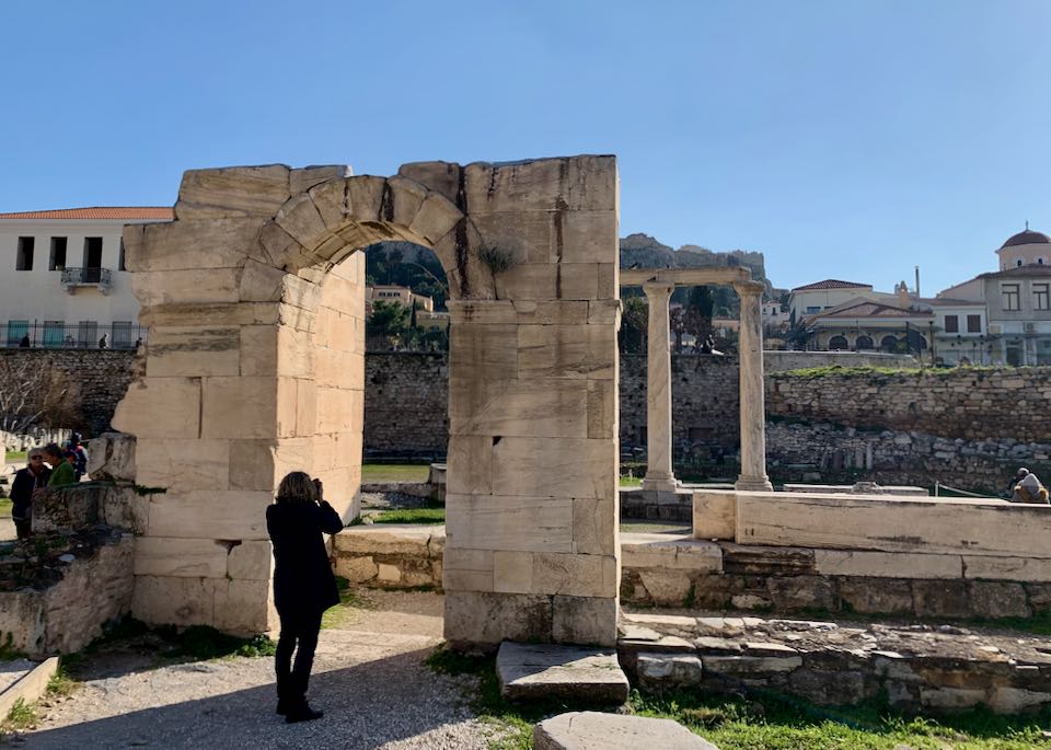 A woman takes a photo through a doorway in an archaeological site