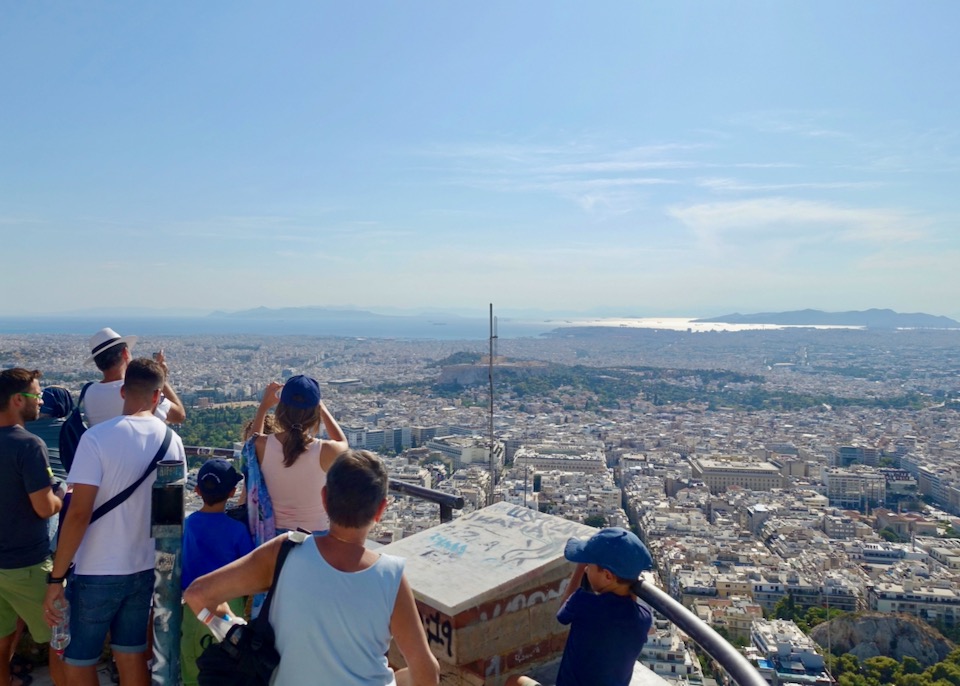 Visitors look out over a viewpoint over Athens below