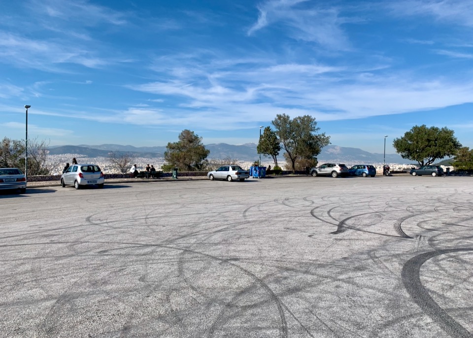 Large, mostly empty parking lot, with views over Athens