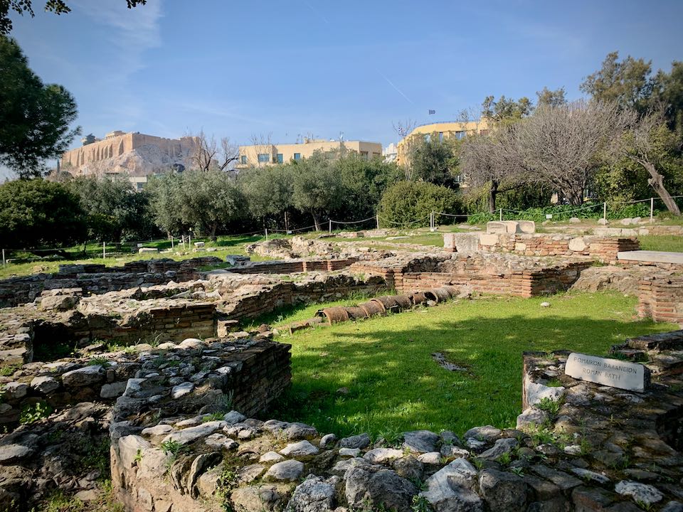 Stone ruins of a Roman Bathhouse, surrounded by grass and trees