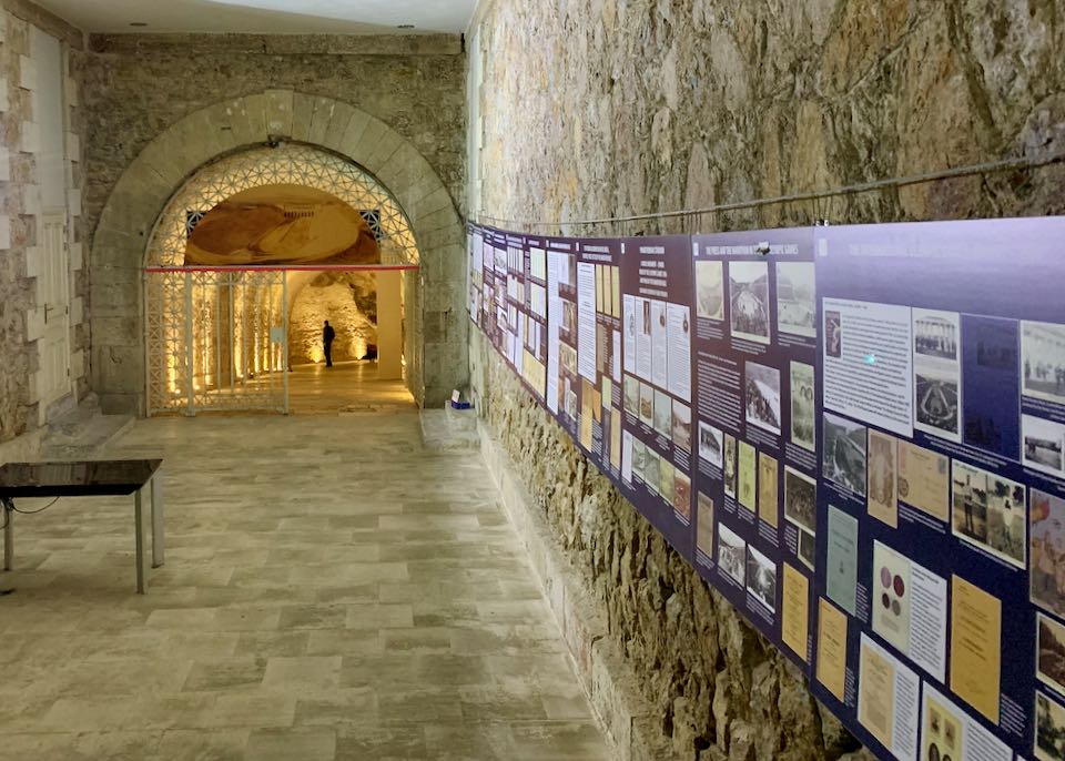 Vaulted tunnel ending in a large marble room with informational wall displays.