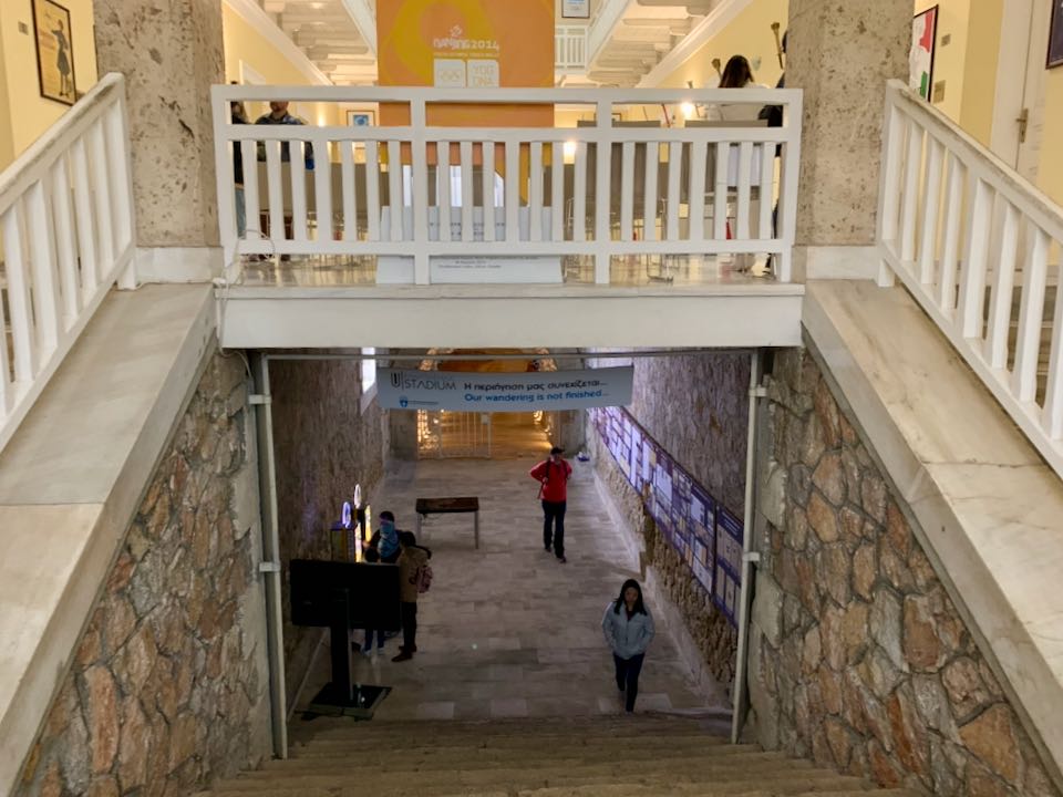 Stairs connecting an old-looking stone tunnel to a modern museum gallery space.